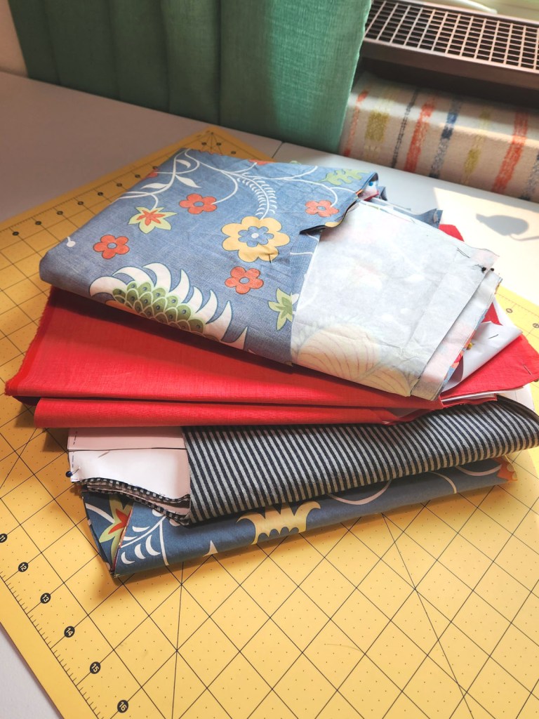 A stack of garment sewing projects cut out and ready to assemble. 