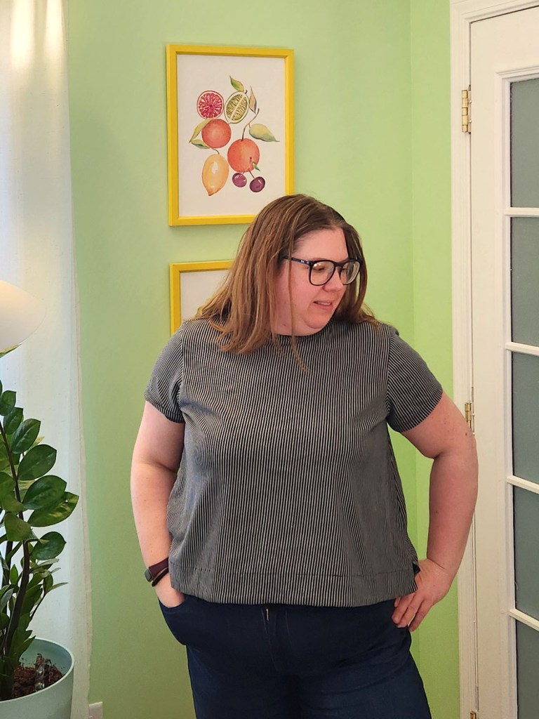 A woman modeling a handmade Love Notions Barrington Boxy Tee made from vertical striped gray and black jersey fabric, styled with dark denim.