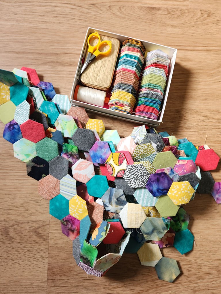 English Paper Piecing hexagon work in progress using fabric scraps. 