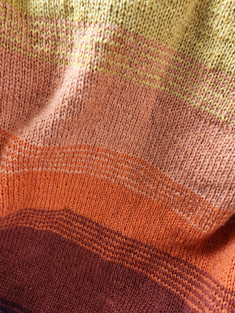 Close up of the So Faded sweater stripes showing the transition between shades of yellow and orange. 
