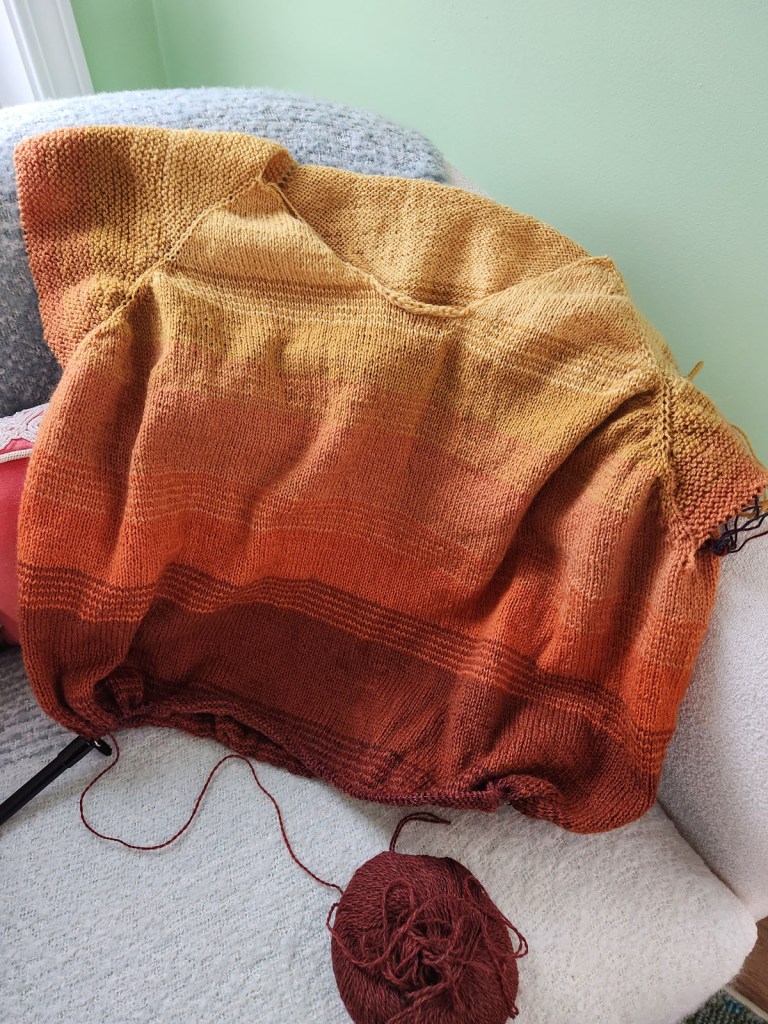 Drea Renee Knits So Faded sweater work-in-progress using Knit Picks yarn in a variety of yellow and orange shades fading from bright yellow at the neckline to dark rusty orange at the hem. 